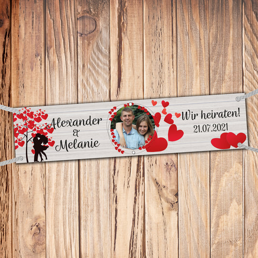 Banner zur Hochzeit mit Namen und Foto personalisierbar. Schriftzug: wir heiraten. Liebespaar unter Herzbaum und viele Herzen.